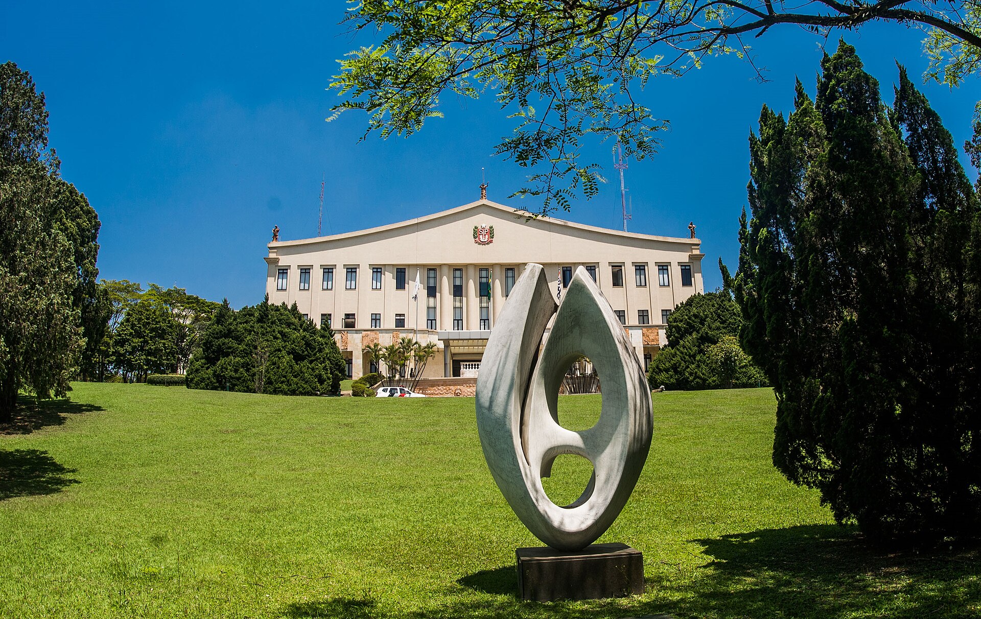 Fachada do Palácio dos Bandeirantes no Morumbi, jardim e escultura em primeiro plano.