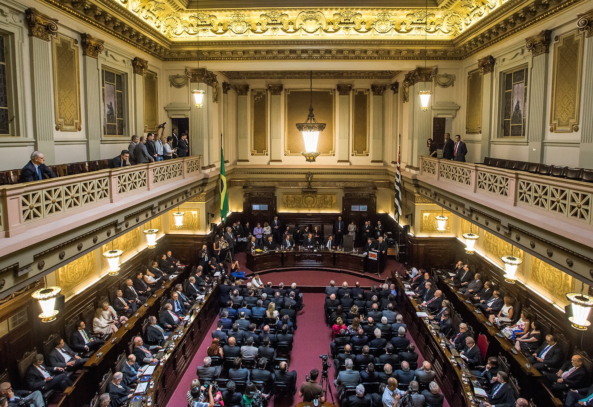Salão com galerias, lustre e as bandeiras do Brasil e de São Paulo no Palácio da Justiça.