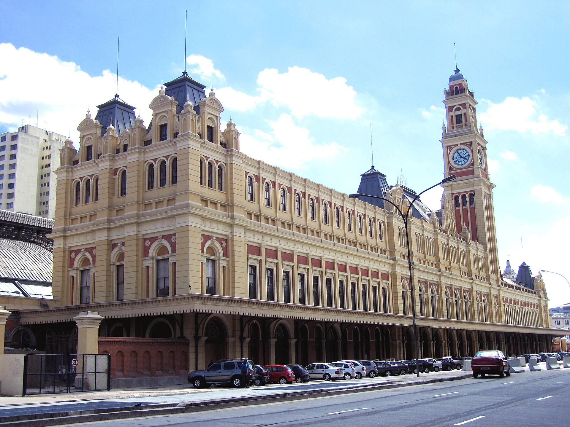 Fachada creme e tijolo da Estação da Luz com a torre do relógio, em São Paulo.