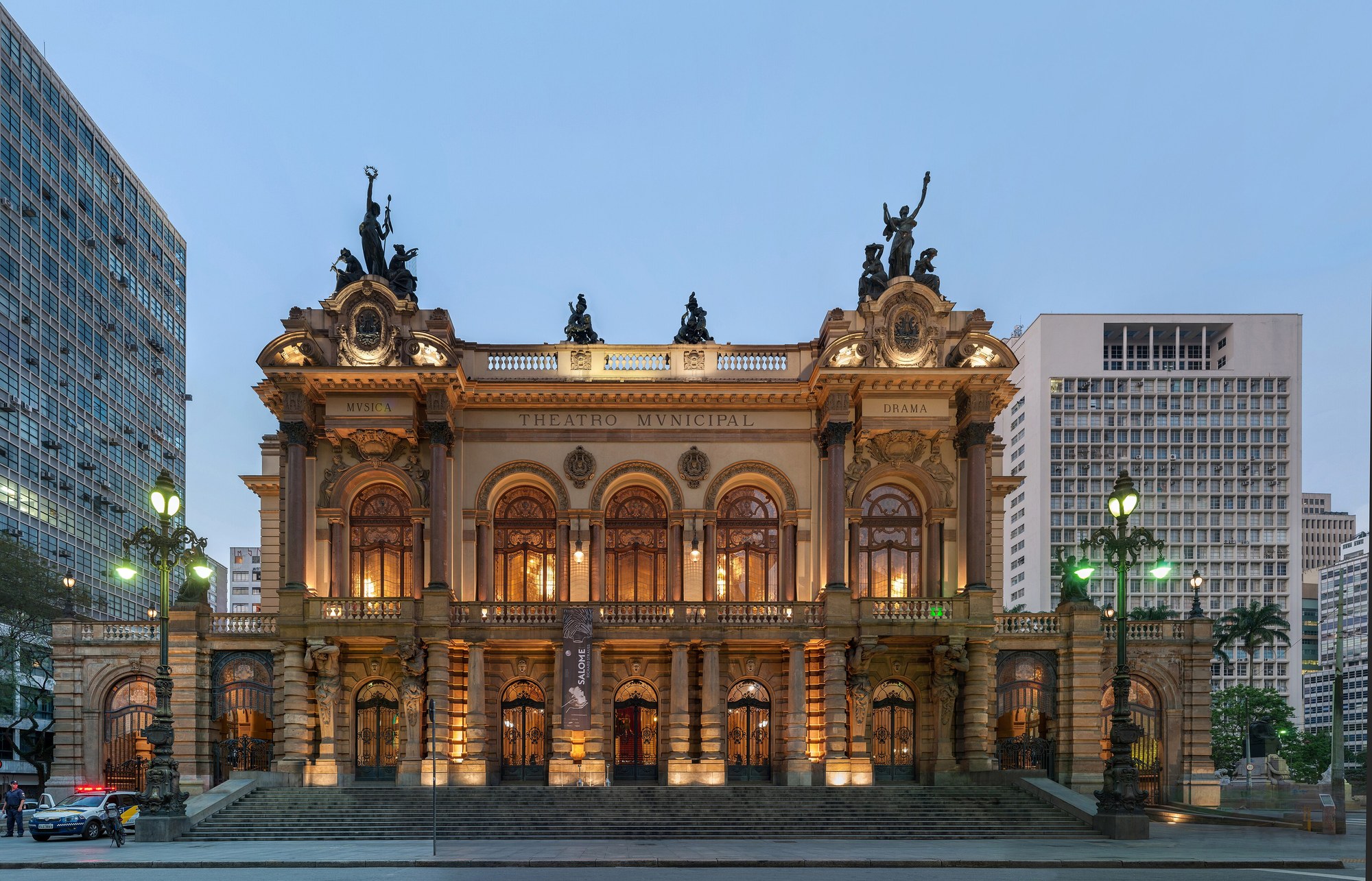 Fachada do Theatro Municipal de São Paulo ao entardecer, com as palavras Musica e Drama nas alas.
